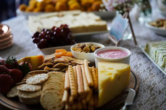 Imagem de mesa com queijo, molho, oleaginosas e snacks